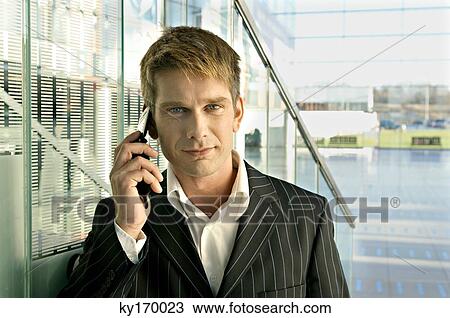Portrait of a businessman talking on a mobile phone at an airport View Large Photo Image Stock Image - Portrait of a businessman talking on a mobile phone at an airport. Fotosearch