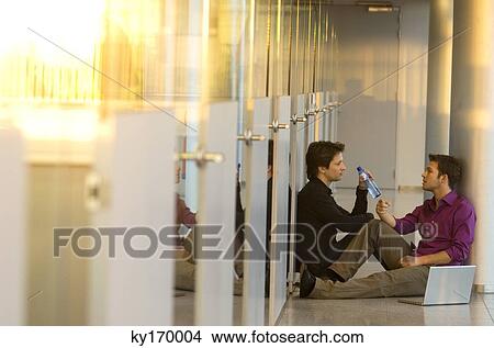 Two businessmen sitting in a corridor and talking with each other View Large Photo Image Picture - Two businessmen sitting in a corridor and talking with each other. Fotosearch