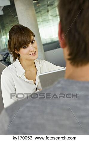 Young woman using a laptop and looking at a mid adult man View Large Photo Image Stock Image - Young woman using a laptop and looking at a mid adult man. Fotosearch