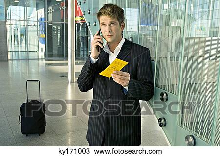 Businessman holding an airplane ticket and talking on a mobile phone View Large Photo Image Stock Image - Businessman holding an airplane ticket and talking on a mobile phone. Fotosearch