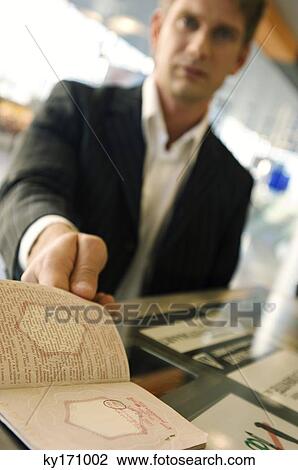 Businessman showing his passport at the airport check-in counter View Large Photo Image Stock Image - Businessman showing his passport at the airport check-in counter. Fotosearch