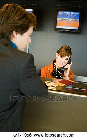 Businessman standing at an airport check-in counter while the check-in attendant talking on the telephone View Large Photo Image Stock Photograph - Businessman standing at an airport check-in counter while the check-in attendant talking on the telephone. Fotosearch