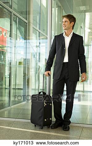 Businessman standing with his luggage at an airport View Large Photo Image Stock Image - Businessman standing with his luggage at an airport. Fotosearch