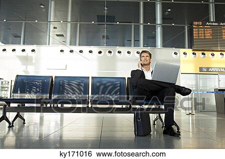 Stock Photograph - Businessman using a laptop and talking on a mobile phone. Fotosearch
