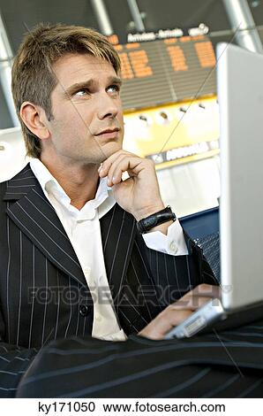 Businessman using a laptop at an airport lounge View Large Photo Image Stock Image - Businessman using a laptop at an airport lounge. Fotosearch