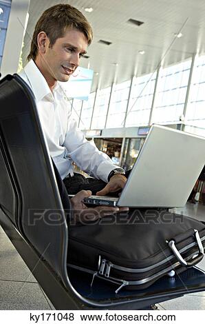 Businessman using a laptop at an airport lounge View Large Photo Image Stock Photo - Businessman using a laptop at an airport lounge. Fotosearch