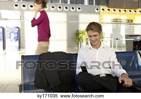 Businessman using a mobile phone at an airport lounge View Large Photo Image Stock Photography - Businessman using a mobile phone at an airport lounge. Fotosearch