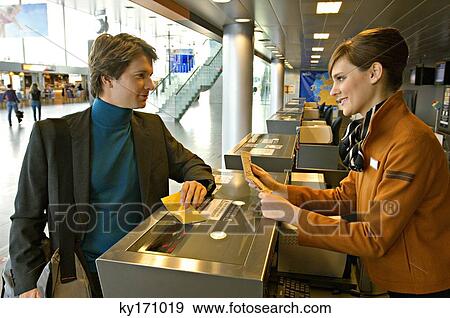 Stock Photo - Businessman with a female check-in attendant at an airport check-in counter. Fotosearch
