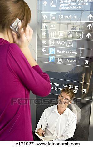Businesswoman talking on a mobile phone with a businessman sitting in front of her View Large Photo Image Stock Photo - Businesswoman talking on a mobile phone with a businessman sitting in front of her. Fotosearch