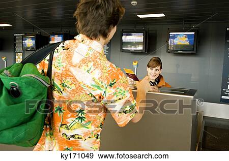 Female airline check-in attendant giving a passport and boarding pass to a passenger View Large Photo Image Stock Photo - Female airline check-in attendant giving a passport and boarding pass to a passenger. Fotosearch