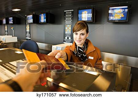 Stock Photo - Female airline check-in attendant giving a passport and boarding pass to a passenger. Fotosearch