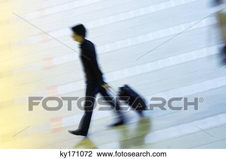 High angle view of a man pulling his luggage at an airport lobby View Large Photo Image Stock Image - High angle view of a man pulling his luggage at an airport lobby. Fotosearch