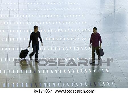 High angle view of a mid adult man and a young man walking at an airport lobby View Large Photo Image Stock Photo - High angle view of a mid adult man and a young man walking at an airport lobby. Fotosearch