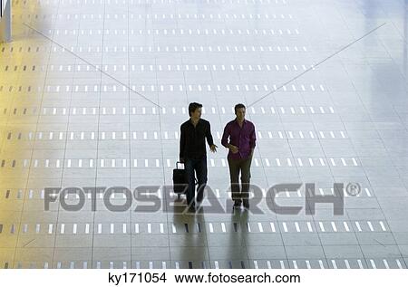 High angle view of a mid adult man walking with a young man at an airport lobby View Large Photo Image Picture - High angle view of a mid adult man walking with a young man at an airport lobby. Fotosearch
