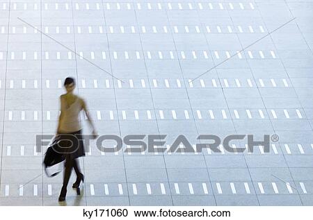 High angle view of a woman walking at an airport lobby View Large Photo Image Stock Image - High angle view of a woman walking at an airport lobby. Fotosearch
