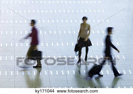 High angle view of three passengers walking at an airport lobby View Large Photo Image Picture - High angle view of three passengers walking at an airport lobby. Fotosearch