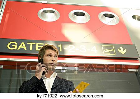 Low angle view of a businessman holding a boarding pass and talking on a mobile phone View Large Photo Image Stock Image - Low angle view of a businessman holding a boarding pass and talking on a mobile phone. Fotosearch