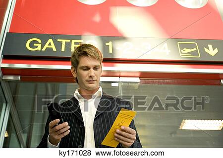 Low angle view of a businessman holding a boarding pass and using a mobile phone View Large Photo Image Stock Photo - Low angle view of a businessman holding a boarding pass and using a mobile phone. Fotosearch