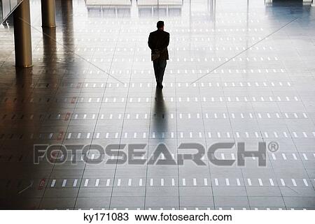 Stock Image - Man walking at airport, rear view. Fotosearch