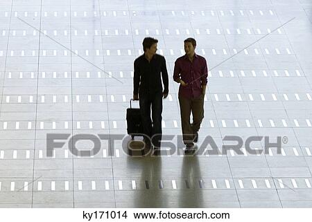 Mid adult man walking with a young man at an airport View Large Photo Image Picture - Mid adult man walking with a young man at an airport. Fotosearch