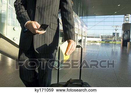 Mid section view of a businessman using a mobile phone at an airport View Large Photo Image Stock Photo - Mid section view of a businessman using a mobile phone at an airport. Fotosearch