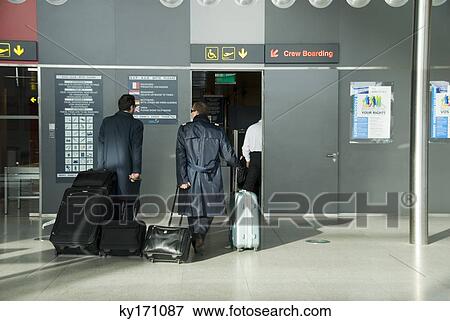 Pilots with luggage at airport, rear view View Large Photo Image Stock Photo - Pilots with luggage at airport, rear view. Fotosearch