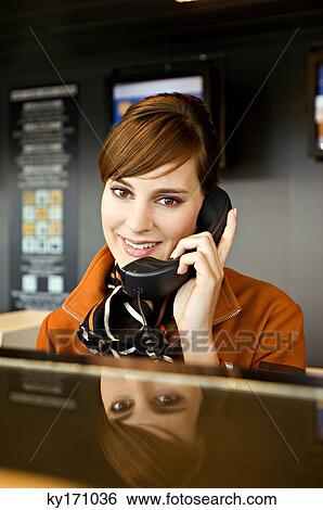 Stock Photograph - Portrait of an airline check-in attendant talking on the telephone. Fotosearch