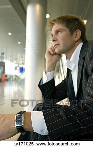Stock Photography - Side profile of a businessman sitting at an airport lounge. Fotosearch