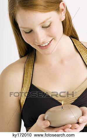 Close-up of a young woman holding a burning candle and smiling View Large Photo Image Stock Image - Close-up of a young woman holding a burning candle and smiling. Fotosearch