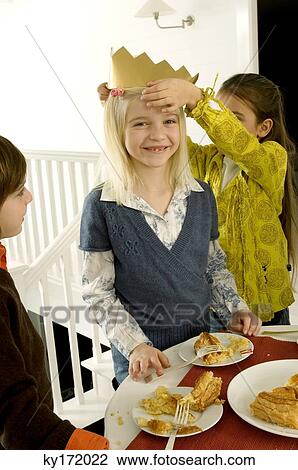 Stock Image - Girl putting a crown on her friend's head. Fotosearch