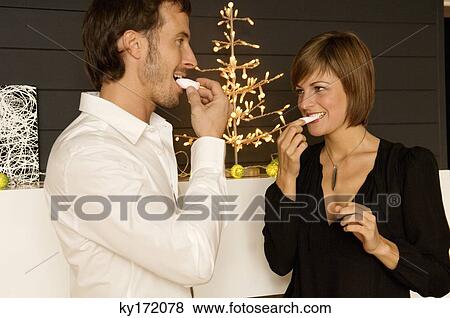 Stock Photo - Mid adult man and a young woman eating candies. Fotosearch