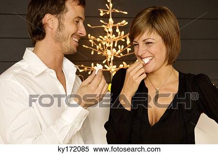 Stock Photography - Mid adult man and a young woman eating candies. Fotosearch