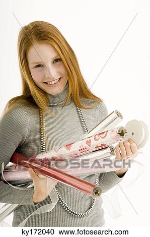 Stock Image - Portrait of a young woman holding rolls of wrapping papers and smiling. Fotosearch