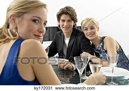 Stock Image - Two young women with a teenage boy at a dinner party. Fotosearch
