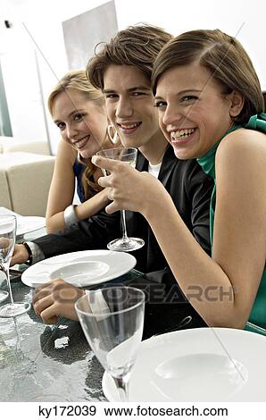Two young women with a teenage boy at a dinner party View Large Photo Image Stock Photo - Two young women with a teenage boy at a dinner party. Fotosearch