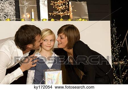 Young woman and a mid adult man kissing their daughter View Large Photo Image Picture - Young woman and a mid adult man kissing their daughter. Fotosearch