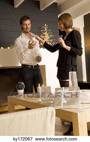 Young woman giving a Christmas ornament to a mid adult man View Large Photo Image Stock Photo - Young woman giving a Christmas ornament to a mid adult man. Fotosearch