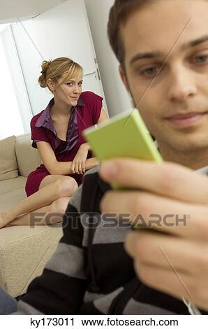 Close-up of a young man holding an MP3 player with a young woman sitting behind him View Large Photo Image Stock Image - Close-up of a young man holding an MP3 player with a young woman sitting behind him. Fotosearch