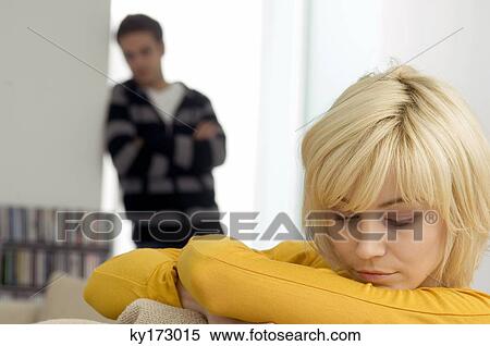 Close-up of a young woman looking sad with a young man standing in the background View Large Photo Image Stock Photography - Close-up of a young woman looking sad with a young man standing in the background. Fotosearch