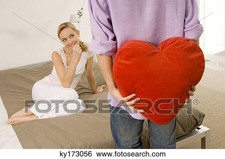 Mid section view of a young man hiding a gift from a young woman View Large Photo Image Stock Photograph - Mid section view of a young man hiding a gift from a young woman. Fotosearch