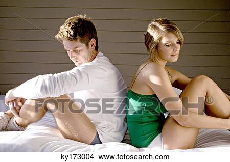 Side profile of a mid adult man and a young woman sitting back to back on the bed View Large Photo Image Picture - Side profile of a mid adult man and a young woman sitting back to back on the bed. Fotosearch