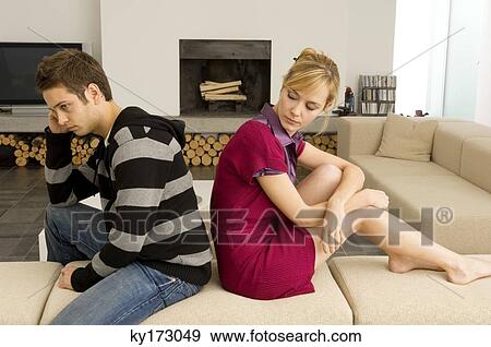 Side profile of a young couple sitting back to back and looking serious View Large Photo Image Stock Photo - Side profile of a young couple sitting back to back and looking serious. Fotosearch