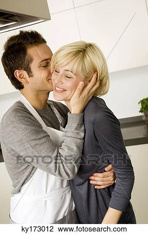 Side profile of a young man kissing a young woman in the kitchen View Large Photo Image Stock Image - Side profile of a young man kissing a young woman in the kitchen. Fotosearch