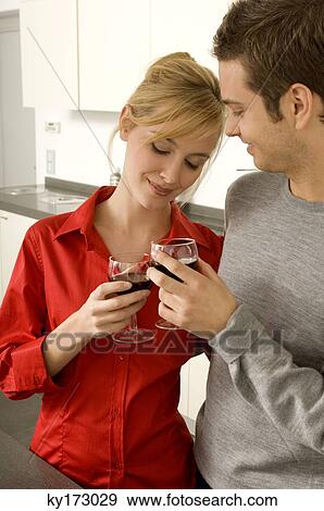 Young couple toasting with wine glasses in the kitchen View Large Photo Image Stock Photo - Young couple toasting with wine glasses in the kitchen. Fotosearch
