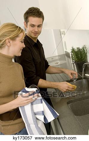 Young man helping a young woman in the domestic kitchen View Large Photo Image Stock Photo - Young man helping a young woman in the domestic kitchen. Fotosearch