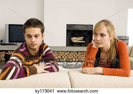 Young man leaning on a couch with a young woman looking at him View Large Photo Image Stock Image - Young man leaning on a couch with a young woman looking at him. Fotosearch