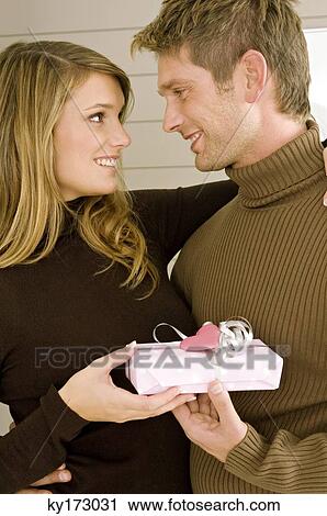 Young woman giving a gift to a mid adult man View Large Photo Image Stock Image - Young woman giving a gift to a mid adult man. Fotosearch