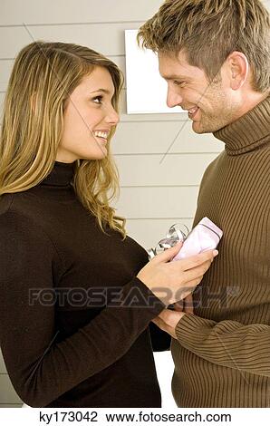 Young woman giving a gift to a mid adult man View Large Photo Image Stock Image - Young woman giving a gift to a mid adult man. Fotosearch