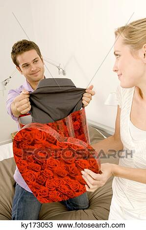 Stock Image - Young woman giving a gift to a young man. Fotosearch