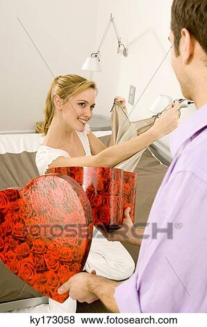 Young woman showing a dress to a young man View Large Photo Image Stock Photo - Young woman showing a dress to a young man. Fotosearch